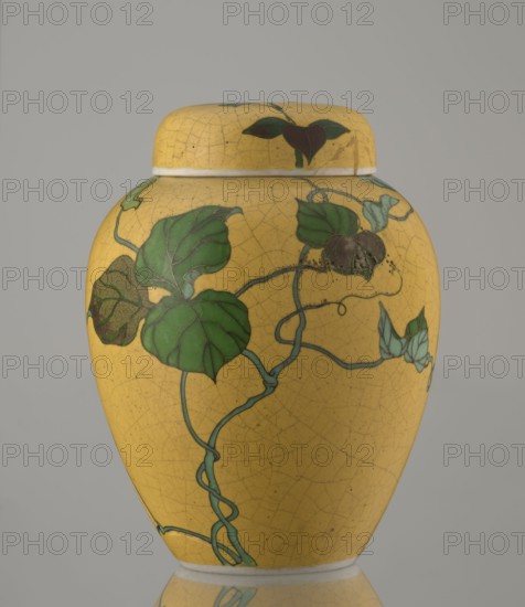 Ginger vessel with lid, Nagoya Shippô Kaisha 1871–1890. Japanese, Meiji period c. 1870–1880. Porcelain cloisonné totai-shippo technique, small ovoid vase with round flattened lid, height 12.4 cm, diameter 9.6 cm. Outer surface covered with lemon-yellow glaze with crackle grid; interior and bottom white covered with transparent glaze. Decorated with a naturalistic bean-vine motif of greenish-brown leaves and pink flowers, loosely twining around the body and reaching the lid. Motif executed in cloisonné enamel with brass wires and multiple shades of enamel; decorative motif was carved into the vessel’s surface before filling with enamel. Signature in cobalt underglaze: Nihon Shippo Kaisha sei zo; overglaze red-iron stamp: a rhombus with the sign sho presumed exporter’s mark. Attributed techniques and makers: Tsukamoto Kaisuke developed porcelain cloisonné c. 1868; similar works made by Takeuchi Chubei and Suzuki Seiichiro; possible attribution to a Nagoya craftsman employed by Nihon Ship...
