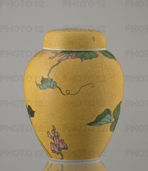 Ginger vessel with lid, Nagoya Shippô Kaisha c. 1870–1880, Meiji period. Small ovoid porcelain vase with a round flattened lid. Exterior covered with a lemon-yellow glaze with a decorative grid of crackles; interior and bottom white with transparent glaze. Decorated with a naturalistic bean-vine motif of greenish-brown leaves and pink flowers, twining around the body and reaching the lid. Motif executed in cloisonné enamel using brass wires and multiple shades of enamel; motif was carved into the vessel’s surface prior to enameling totai-shippo technique. Porcelain cloisonné technique developed around 1868 by Tsukamoto Kaisuke; similar wares also made by Takeuchi Chubei and Suzuki Seiichiro; Takeuchi Chubei was among prominent craftsmen employed by Nihon Shippo Kaisha and this piece may be by him though unsigned. Signature in cobalt underglaze: Nihon Shippo Kaisha sei zo; overglaze red iron rhomboid cartouche with the sign sho. Nagoya, Japan. Vessel; height 12.4 cm, diameter 9.6 cm. Cl...