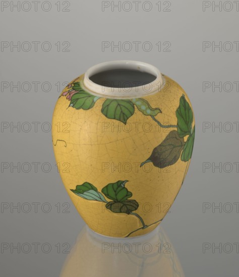 Ginger vessel with lid, Nagoya Shippô Kaisha c. 1870–1880, Meiji period. Small ovoid porcelain vase with round flattened lid; exterior covered with lemon-yellow glaze with crackle grid, interior and base white with transparent glaze. Decorated with a naturalistic bean-vine motif of greenish-brown leaves and pink flowers, loosely twining around the body and reaching the lid. Motif executed with cloisonné enamel technique using brass wires and multiple enamel shades; motif was carved into the vessel surface prior to enameling totai-shippô technique. Porcelain cloisonné method developed around 1868 by Tsukamoto Kaisuke; similar works made by Takeuchi Chubei and Suzuki Seiichiro, and possibly by Takeuchi Chubei though this object is unsigned. Underglaze cobalt inscription: Nihon Shippo Kaisha sei zo; overglaze red-iron rhomboid stamp with sign sho. Porcelain; height 12.4 cm, diameter 9.6 cm., A rounded ceramic vase with a glossy yellow surface showing a fine crackle pattern, decorated with...