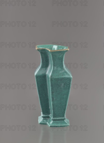 Vase; creator, : Ignacy Jan Paderewski 1860–1941; Chinese; Qing dynasty 1644–1911; 19th century; ceramic vessel covered with a turquoise glaze with manganese spots; height 11.6 cm, width 4.9 cm, depth 7.1 cm, weight 0.15 kg., A ceramic vase with a glossy teal surface and speckled texture stands against a plain neutral gray background, showing a pair of joined, faceted bodies that taper inward toward a flared rim with a thin band of muted gold along the edge; the vase rests on a small hexagonal base and displays subtle variations of teal and darker greenish-blue tones across its surfaces.