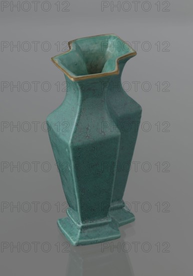 Vase, Chinese, Qing dynasty 1644–1911, ceramics; covered with a turquoise glaze with manganese spots. 19th century, China. Vessel; height 11.6 cm, width 4.9 cm, depth 7.1 cm, weight 0.15 kg., A green ceramic vase with a textured surface and a flared, irregular square rim edged in a gold color, standing on a stepped square base and reflected faintly on a smooth gray surface; the vase shows varying shades of green and some darker speckled patterns.