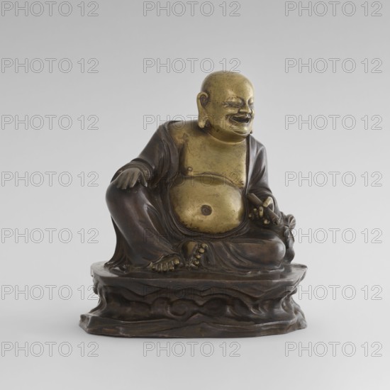 Monk Budai Laughing Buddha, gift; Chinese art, Chinese, Qing 1644–1911; Buddhist art; Chinese Buddhism; Buddha of the Future, Budai iconography, Maitreya; described by donor as Chinese deity of Burmese origin from Shah province; 19th–20th century, China place of origin, Burma Myanmar place of acquisition; sculpture; height 22.3 cm, width 23.0 cm, depth 16.0 cm, A small bronze statue of a seated, smiling figure with a rounded belly and relaxed posture sits on a carved base; the figure shows a contrast of darker brown bronze drapery and a brighter golden-bronze skin on the head, chest, and abdomen, with detailed hands and feet resting on the lap and knees, and folds of the robe cascading over the pedestal which is a darker brown with carved wave-like patterns.