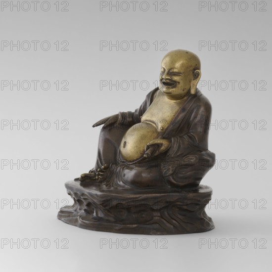 Monk Budai Laughing Buddha, gift, Chinese art; Chinese culture; Qing dynasty 1644–1911; Buddhist art; Chinese Buddhism; Buddha of the Future, Budai iconography, Maitreya; described by the donor as a Chinese deity of Burmese origin from Shah province; 19th/20th century; China place of origin, Burma Myanmar place of acquisition; sculpture; height 22.3 cm, width 23.0 cm, depth 16.0 cm, A small bronze and gold-toned statue of a seated, smiling figure with a rounded belly sits on an irregularly shaped, textured base. The figure's head, chest, and belly have a gold color while the robes, hands, and base are darker bronze brown. The figure's facial features are sculpted with closed eyes and a broad smile, and one hand rests on the belly while the other hand extends outward. The drapery of the robes shows folds and contours in the darker bronze, and the base has carved, wave-like patterns in similar brown tones. The background is a smooth, light gray.