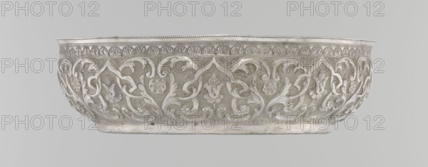 Bowl, Islamic art, Turkish, Ottoman dynasty 1299–1922, silver hammam bowl, geometric motifs and plant ornament, tugra of Abdulhamid II 1842–1918, 1876–1909, Turkey; vessel; height 5.6 cm, diameter 19.0 cm., A decorative bowl with an ornate relief pattern around its exterior, featuring flowing floral and foliate motifs in raised relief; the rim has a band of repetitive decorative detailing and a beaded edge; the bowl's surface shows smooth and textured areas with subtle variations in sheen; visible colors include silver, light gray, and a few darker gray tones.