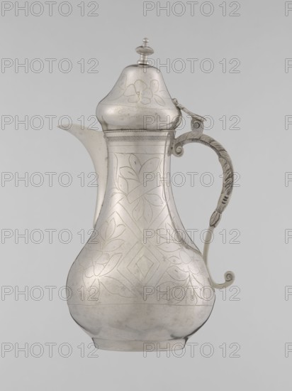 Teapot with a lid, Ottoman Turkish, 19th century, vessel for beverages, teapot, silver?, geometric motifs and plant ornament, height 20.3 cm, diameter 9.7 cm, weight 300 g., A metal pitcher with a bulbous body, a curved spout, and a hinged domed lid topped by a finial; the surface shows etched floral and geometric patterns and a decorative band near the neck; a curved handle with ornamental carving and a curled lower end is attached at the side; the object is shown against a plain light gray background and appears in shades of silver and gray.