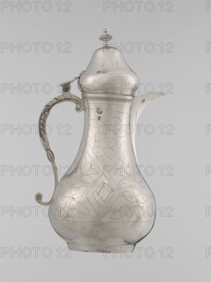 Teapot with a lid; maker, 19th century Ottoman Turkey; Turkish, Islamic art; vessel for beverages teapot; geometric motifs and plant ornament; height 20.3 cm, diameter 9.7 cm, weight 300 g., A metal jug with a curved pear-shaped body and a domed lid, shown against a plain light gray background, with a decorative handle featuring a curled end and textured patterning, a short spout extending from the upper body, and engraved floral and geometric decorations across the body; visible colors include silver tones and shades of gray.