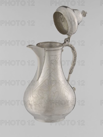 Teapot with a lid, creator unknown, Islamic art, Turkish, Ottoman dynasty 1299–1922, beverages, teapot, geometric motifs, plant ornament, 19th century, Turkey, vessel, weight 300 g, height 20.3 cm, diameter 9.7 cm, A metallic pitcher with a hinged domed lid is shown against a plain light gray background; the pitcher is silver in color with a bulbous body that tapers to a narrower neck and a pronounced spout, and it features engraved floral and geometric patterns on its surface; a curved handle with decorative ridges and a hinge attaches the lid, which is open to reveal the interior of the lid and the rim; the interior surfaces appear slightly darker and more matte than the polished exterior, and the overall tones in the image include silver, light gray, and subtle darker gray areas.