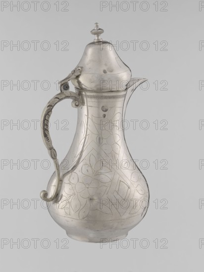 Teapot with a lid, Islamic art, Turkish, Ottoman dynasty 1299–1922, beverages, teapot, geometric motifs, plant ornament, 19th century, Turkey, vessel, weight 300 g, height 20.3 cm, diameter 9.7 cm, A silver pitcher with a bulbous body, a curved spout, and a domed lid topped by a finial is shown; the body and lid have etched floral and geometric patterns, and the handle is ornate with a scrolling shape and decorative ridges. The visible colors are silver tones and hints of gray, set against a pale gray background.