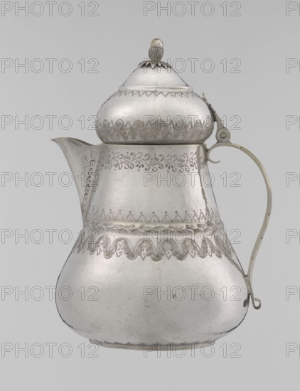 Teapot; maker, 19th century, Turkey Ottoman dynasty, 1299–1922; Islamic art, Turkish; silver vessel; teapot/jug form; height 17.0 cm, diameter 10.9 cm, weight 320 g; decorated with geometric motifs, plant ornament including lambrequin, zigzag patterns., A silver-colored metal pitcher with a bulbous lower body tapering to a narrower midsection and a rounded lid topped by a small finial, featuring engraved decorative patterns around the midsection, near the top, and along the lower shoulder; a curved spout extends from one side and a thin, curved handle with a small curled end attaches on the opposite side; the surface shows areas of slight tarnish and subtle scratches, and the background is a pale gray.