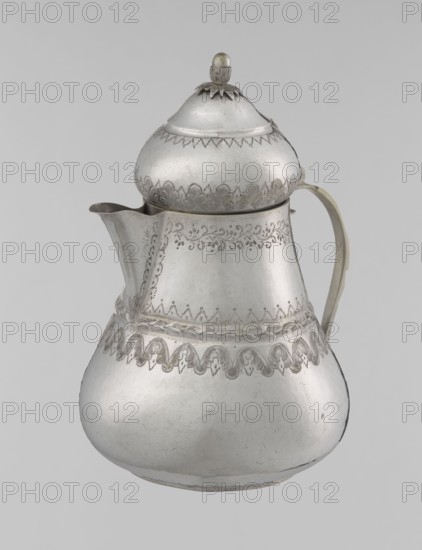 Teapot, 19th century, Turkey; Islamic art, Turkish, Ottoman dynasty 1299–1922; teapot vessel, weight 320 g, height 17.0 cm, diameter 10.9 cm; materials/technique not specified; decoration: geometric motifs, plant ornament, zigzag, lambrequin., A silver-colored metal pitcher with a rounded base, a narrower midsection, and a domed lid topped by a small finial, showing engraved decorative patterns around the upper body, midsection, and near the base; it has a curved spout on one side and a curved handle on the opposite side, with the metal surface showing slight tarnish and subtle scratches, and the overall background appearing light gray.