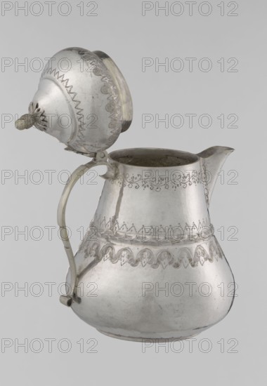 Teapot, 19th century, Turkey; Ottoman dynasty 1299–1922; Islamic art, Turkish; teapot vessel, height 17.0 cm, diameter 10.9 cm, weight 320 g; materials not specified; decorated with geometric motifs, plant ornament, zigzag, lambrequin., A metal pitcher with a hinged lid is shown against a plain light gray background; the pitcher has a bulbous lower body tapering to a narrower neck and a short spout, a curved handle attached along the side, and the lid is open and connected by a hinge. The surface of the pitcher shows decorative punched and engraved bands around the upper and middle sections with scalloped and floral-like motifs and a raised braided band encircling the midsection; the lid has matching decorative edging and a small knob. The visible colors are silver-gray of the metal with areas of darker gray patina and some faint off-white or yellowed discoloration on the hinge and handle.