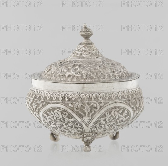 Vessel with a lid, Islamic art, Turkish, Ottoman dynasty 1299–1922, plant ornament, flowers, plant tendril, marked coat of arms, 19th century, Turkey, vessel, weight 240 g, height 11.7 cm, diameter 10.5 cm, An ornate lidded bowl with an embossed surface rests on a plain light background; the bowl and lid are decorated all over with raised floral and foliate patterns and scrolling motifs, with a conical lid topped by a finial and the body standing on a few rounded feet; the visible colors are silver and shades of gray.