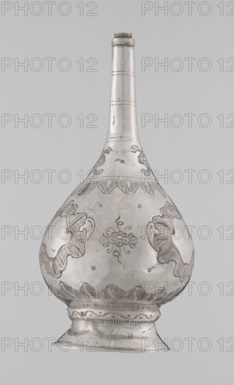 Bottle for spraying water soaked in perfumes, Islamic art; vessel with plant and floral ornament: multi-leafed undecorated cartouches alternating with small flowers; 19th/20th century; Turkey, / North Africa ; weight 113 g; height 17.5 cm; diameter 8.0 cm., A single metallic vessel with a long narrow neck and a rounded, bulbous body resting on a flared foot is shown against a plain light gray background. The vessel appears silver in color with darker engraved areas creating decorative patterns; the surface shows polished highlights and subtle variations of gray and reflective sheen. The bulbous body features engraved floral and foliate motifs including stylized flower clusters and petal-like shapes, with several scalloped bands encircling the widest part. The neck is smooth with a few incised horizontal bands and faint surface marks, and the foot has molded ridges and a repeating decorative engraved band around its upper edge. The overall appearance is metallic gray and silver with fin...