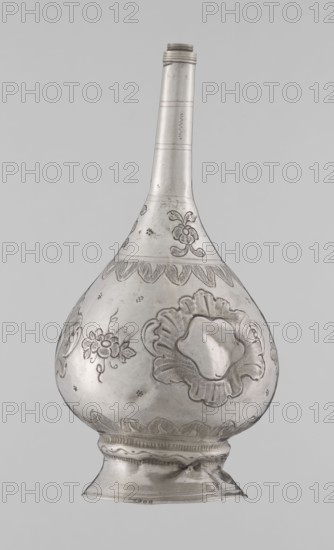 Bottle for spraying water soaked in perfumes, Islamic art, Islamic culture; vessel with plant and floral ornament; decoration: multi-leafed undecorated cartouches alternating with small flowers; 19th–20th century; origin: Turkey, or North Africa ; weight 113 g; height 17.5 cm; diameter 8.0 cm., The image shows a metallic vessel with a long narrow neck and a bulbous body sitting on a flared foot, all rendered in silvery-gray tones; the body is decorated with engraved floral motifs including a few stylized flowers and leafy patterns, raised scalloped borders, and punched dotted textures, with visible surface scratches and slight dents, and the background is a uniform light gray.