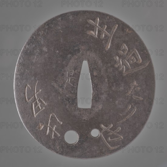 Crossguard tsuba, Korekazu,  school author, Amida iconography, sword crossguards, katana, Japanese art, Buddha iconography, Japanese culture, Edo 1603-1868, weapon, bladed weapons, inscriptions, Buddhism. Oval tsuba tatemaru gata with a rectangular edge kaku mimi. In the lower part there are two holes udenuki ana for threading the ribbon. The surface of the shield is decorated on both sides with an inscription engraved in cursive script. On the obverse, an invocation to Amida Buddha: Namu Amida butsu praise be to Amida Buddha; on the reverse, the inscription: Iki sugi tarinari kono otoko this man has lived too long. Signed. 17th century Edo period 1603-1868 Enpô era 1673-1681, Japan, Ômi Eshu province, tsuba, height 9.1 cm, width 8.6 cm, depth 0.3 cm., A round, flat metal object with a central tapered triangular hole and two smaller circular holes near the bottom, showing a worn, textured surface in dark gray and brown tones with areas of lighter gray highlights; a group of shallow car...