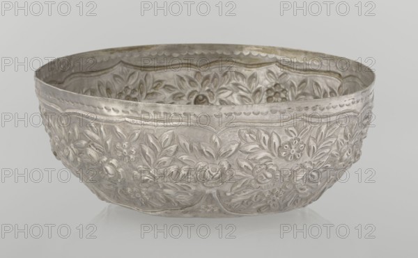 Bowl, Islamic art, Turkish, Ottoman dynasty 1299–1922, floral ornament, plant ornament, wall decorated with floral motifs in the valance, late 19th century, Turkey, vessel, weight 295 g, height 7.0 cm, diameter 18.0 cm, A shallow decorative metal bowl with an embossed floral pattern covering its outer and inner surfaces, showing a group of raised flower and leaf motifs in a repeating band around the bowl. The metal has a silvery gray appearance with subtle darker gray areas that emphasize the embossed detailing and a few slightly warmer, faintly golden tones near the rim. The background is a smooth pale gray that contrasts with the textured surface of the bowl.