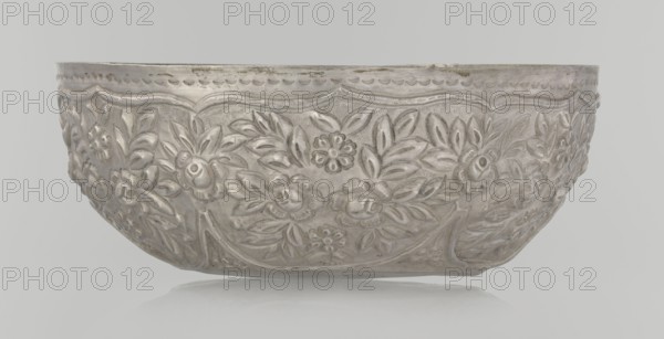 Bowl, late 19th century, Turkey, Ottoman dynasty 1299–1922; ceramic vessel decorated with floral and plant motifs, wall decorated with floral motifs in the valance; weight 295 g; height 7.0 cm; diameter 18.0 cm; Islamic art, Turkish., A shallow rounded bowl with an embossed floral pattern covering its exterior, showing stylized flowers and leaves in relief, with a scalloped decorative rim; the bowl appears metallic with shades of silver and gray, and it sits against a pale gray background that reflects faintly beneath it.