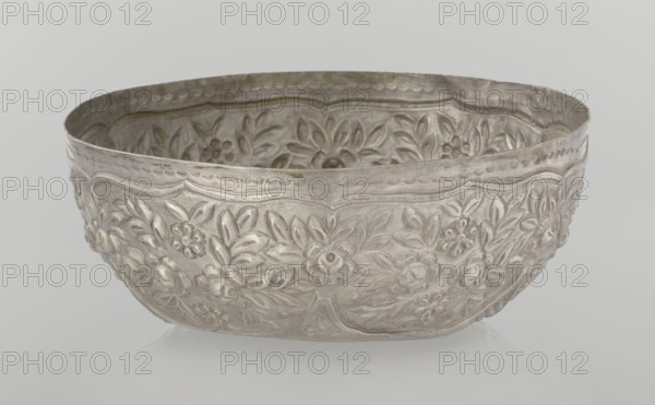 Bowl, late 19th century, Turkey; Ottoman dynasty 1299–1922; vessel, height 7.0 cm, diameter 18.0 cm, weight 295 g; Islamic art, Turkish; decorated with floral and plant motifs, wall decorated with floral motifs in the valance., A shallow metal bowl with an embossed floral pattern covering its exterior and interior, showing raised flowers and leaves in a repeating decorative design; the rim is gently scalloped and the surface has a slightly worn, tarnished appearance. The visible colors are silver and gray with subtle darker gray areas where the metal appears aged.