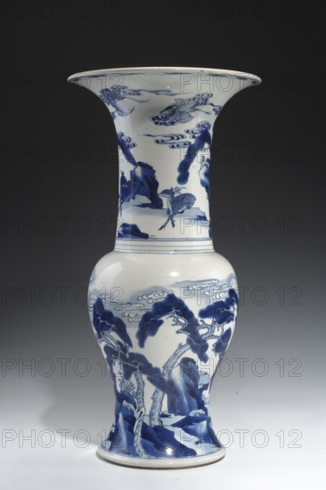 Zun-type baluster vase, ceramics, porcelain, blue and white porcelain, deer, pines, rocks, Kangxi style, Qing style, cranes iconography, Chinese culture, Qing 1644–1911, Kangxi 1662–1722, vase with a baluster body and a long cylindrical neck flaring into a goblet shape, 1662–1722, China, vessel, height 45.7 cm, diameter 23.3 cm, A tall porcelain vase with a flared rim, painted in deep blue on a white background, decorated with a landscape scene that includes stylized trees with sweeping canopies, rock formations, swirling cloud motifs, and a few birds in flight; the upper neck shows additional birds and cloud patterns, while the bulbous body transitions to a narrower foot with tree trunks and rocky ground depicted; the color palette is primarily cobalt blue and white, with subtle glazed highlights and reflections on the ceramic surface.