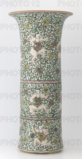 Cylindrical vase of the horn type, Chinese, Qing dynasty Kangxi period, 1662–1722, colored porcelain in the famille verte green family palette, height 37.5 cm, diameter 18.0 cm, weight 2.35 kg; decorated with lotus tendril ornament and belt decoration., A tall flared ceramic vase with an off-white background densely decorated with swirling green vine patterns and leaves, featuring a few stylized yellow and brown flowers; several small figures of children with pale skin tones and black hair are depicted in animated poses, wearing green and red garments and holding elements of the vines; thin bands with geometric patterns separate the vase into sections; the rim and base show a muted brownish edge.