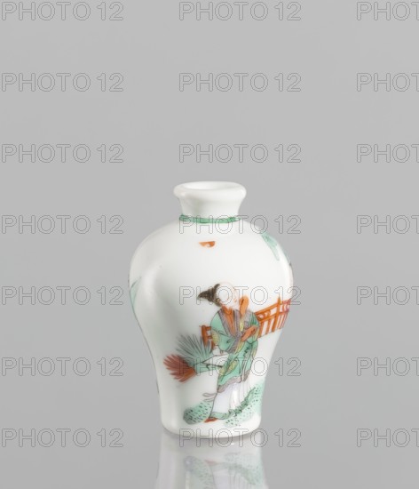 Flask - Snuffbox. A baluster-shaped flask, significantly widened at the shoulders. Thick white porcelain body. Decoration includes a fragment of landscape and architecture, and images of women in figurative scenes. Colored porcelain snuffbox; 18th century, China. Height 7 cm, diameter 4.7 cm., A small white ceramic vase with a narrow neck and flared rim sits against a light gray background; the vase is painted with a scene showing a figure in a green and orange robe standing near a low orange railing, with green foliage and a reddish fan-like plant nearby, and additional small green decorative touches around the neck and base.