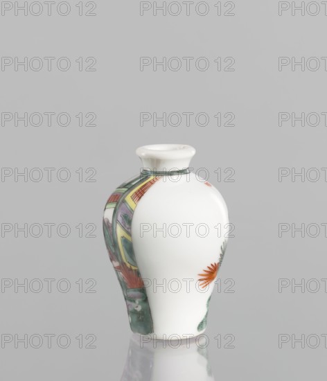 Flask - Snuffbox. Chinese; 18th century. A baluster-shaped colored porcelain flask/snuffbox, significantly widened at the shoulders with a thick white-bodied porcelain white cake. Decoration includes a fragment of landscape and architecture slightly highlighted, with figurative scenes depicting images of women. Vessel; height 6.9 cm, width 4.6 cm., A small rounded porcelain vase with a narrow flared neck sits against a plain gray background; most of its body is glossy white, while one side shows a colorful painted panel with shades of green, yellow, purple, and red forming abstract and architectural shapes, and the opposite side displays a painted orange flower with green leaves; there is a thin gray-green band around the base of the neck and a soft reflection of the vase on the surface below.