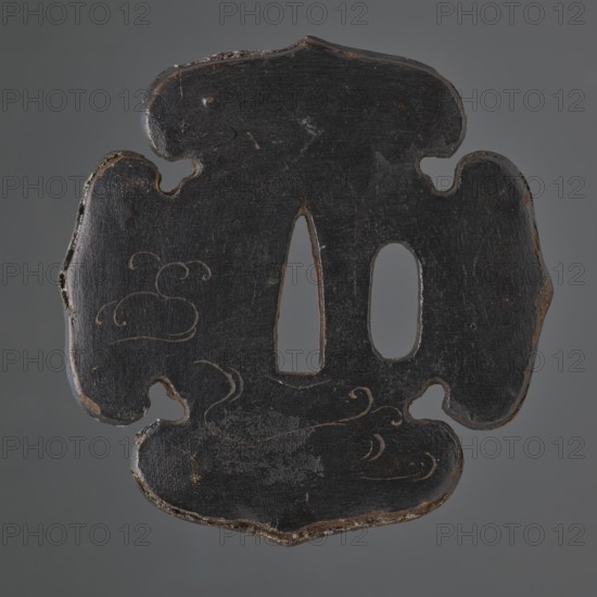 Crossguard tsuba, Japanese, Edo period 17th–18th century. Iron lined with multiple-folded impregnated canvas and covered with matte black lacquer; decorated with colored lacquer reliefs. Tsuba in the shape of an aoi with heart-shaped cutouts between the petals inome — boar's eye, with a kozuka hitsu ana hole. Obverse: relief motif of maple leaves — one red, the other white; reverse: delicately engraved plant twig. Unsigned. Function: sword crossguard katana tsuba. Dimensions: height 8.4 cm, width 8.2 cm, depth 0.5 cm., A roughly symmetrical dark object with an irregular, curving outline and two elongated central cutouts, showing a worn surface texture and edges with exposed lighter material; the surface has subtle carved or incised flowing line motifs and areas of scuffing; visible colors include black, dark brown, lighter brown at the edges, and faint gray highlights against a neutral gray background.