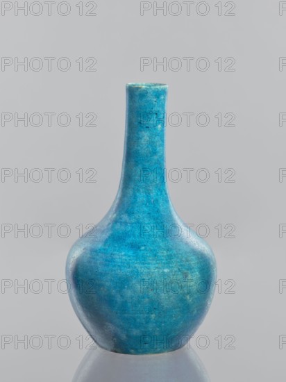 Vase — bottle;, Glazed crackleware ceramic vessel in Qing style, China, 19th–20th century. Height 18.4 cm; diameter 10.8 cm; weight 0.35 kg. Gift; provenance includes Ignacy Jan Paderewski 1860–1941., A rounded vase with a long, narrow neck sits against a neutral pale gray background, its surface showing a mottled turquoise blue with areas of lighter and darker teal, subtle greenish tints, and tiny speckled imperfections; the vase has a smooth, slightly glossy finish and is reflected faintly on the surface beneath it.