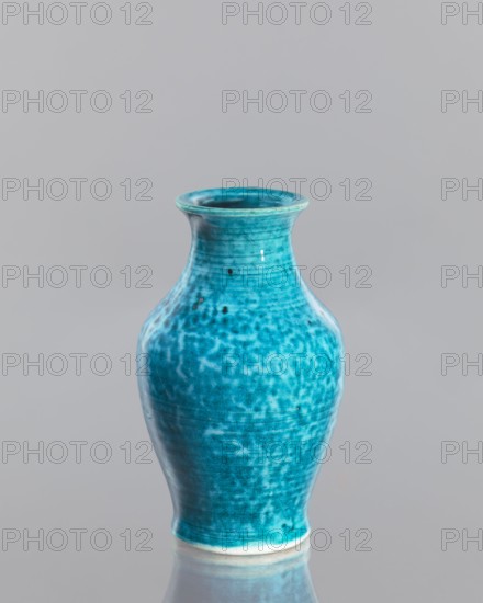 Vase, Chinese, Qing dynasty 1644–1911, 2nd half of the 18th century, glazed crackleware ceramic vessel; height 12.5 cm, diameter 7.6 cm., A glossy ceramic vase with a rounded body that tapers at the neck and flares at the rim sits against a plain background; the vase displays a mottled turquoise blue glaze with lighter and darker blue variations and small dark speckles, a subtle off-white base edge is visible, and the surface reflects light.