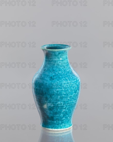 Vase, Chinese, Qing dynasty 1644–1911, 2nd half of the 18th century, glazed crackleware ceramic vessel; height 12.5 cm, diameter 7.6 cm., A smooth ceramic vase in shades of turquoise and teal with a slightly flared rim and a rounded, tapered body sits against a plain light gray background, its glossy surface showing subtle mottled texture and darker blue-green variations, and a narrow lighter band along the base with a soft reflection on the surface beneath.
