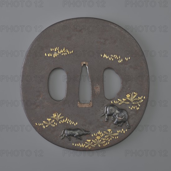 Crossguard tsuba, Ichiryûsai Masamitsu; Shôami school. Oval tsuba tatemaru gata decorated in high relief with colored metals iro-e zôgan: on one side a stream winds among grasses and dandelions; on the other a buffalo and a she-buffalo graze in a flowery meadow. 1st half of the 19th century Edo period, 1603–1868, Japan. Materials: metal with colored-metal inlay. Dimensions: height 7.6 cm; width 7.6 cm; depth 0.4 cm., A round dark brown metal object with three irregular vertical openings near its center, decorated with small areas of bright gold leaf-like shapes and floral motifs, and featuring a few raised dark metallic animal figures, all set against a smooth gray background; visible colors include dark brown, gold, black, and gray.