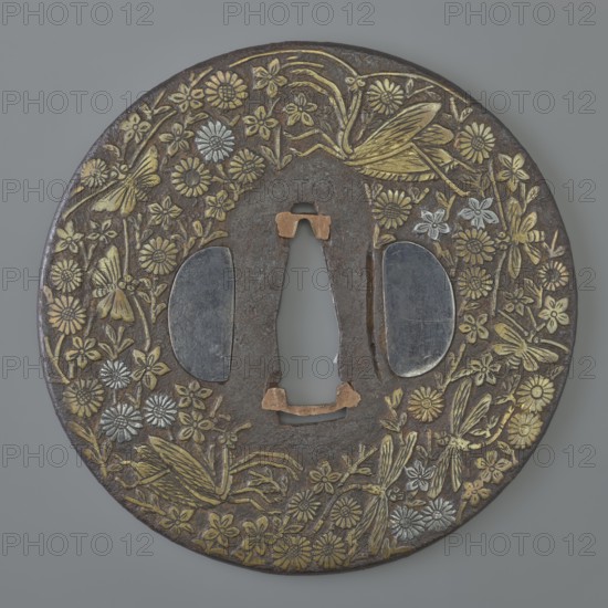 Crossguard tsuba, Mino school/author, Japanese, Edo period 1603–1868, 18th century. Round tsuba maru-gata with rounded edge maru mimi; ryohitsu ana holes plugged with shakudô alloy; copper sekigane. Decorated on both sides with dense, low-relief inlay of brass and silver depicting various flowers with praying mantises, butterflies, and dragonflies. Signed. Diameter 8.3 cm; thickness 0.3 cm., A round metal object with a central irregular cutout, decorated all around with a floral and insect motif; the surface shows a dark brown base metal with patterns in metallic gold and silver tones, and a few areas of dull copper color around the central opening; the design includes several stylized flowers, a group of daisylike blooms, and multiple insects resembling grasshoppers or dragonflies rendered in gold and silver, set against the dark brown field.