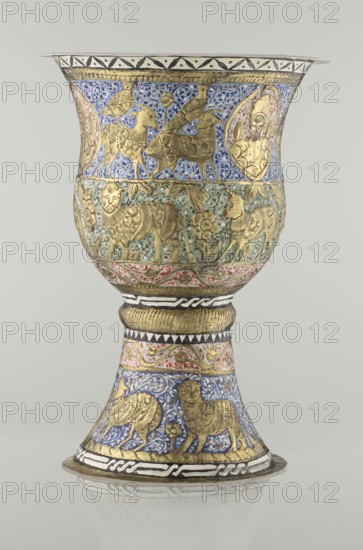 Cup, Persian, Qajar dynasty 1785–1925, 19th century, Iran. Ceramic vessel, height 25.5 cm, diameter 18.4 cm. Decoration: cartouches with a bust of a man, animals lions, birds, figures, flowers, geometric and small plant ornament; figurative motifs., A decorative goblet-shaped object with a flared rim and a rounded bowl on a tapered stem and circular base, richly ornamented with raised metallic figures and painted backgrounds; the surface shows gilded relief animals including winged creatures and feline-like figures, floral and foliate motifs, and framed medallion shapes with human-like busts, all set against painted areas of blue, green, red, white, black, and touches of pink, with patterned bands and geometric borders encircling the form.