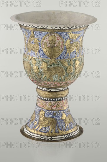 Cup, Persian, Qajar dynasty 1785–1925, 19th century, Iran. Ceramic vessel, height 25.5 cm, diameter 18.4 cm. Decoration: cartouches with a bust of a man, animals lions, birds, figures, flowers, geometric and small plant ornament; figurative motifs., An ornate goblet with a flared rim and a stemmed base, decorated with embossed gold figures and detailed enamel work in blue, green, red, white, black, and gold. The upper bowl shows a band of blue enamel with scrolling floral motifs and gold animal and humanlike medallion decorations, while the middle band has green enamel with gold floral and animal reliefs and a narrow red and white patterned border below. The stem area is wrapped with a gold ribbed collar above a section of red and white enamel ornamentation and a patterned black and white band, and the flared foot displays blue enamel with gold animal figures and additional black, white, and gold geometric borders. The interior of the bowl appears plain and light in color.