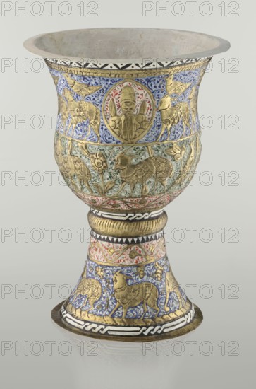 Cup, Persian, Qajar dynasty 1785–1925, 19th century, Iran; ceramic vessel, height 25.5 cm, diameter 18.4 cm. Decoration: cartouches with a bust of a man, animals lions, birds, figures, flowers, geometric and small plant ornament; figurative motifs., A decorative goblet-shaped vessel with a flared rim and a rounded bowl on a tapering pedestal, featuring metallic gold relief figures and animals set against intricate enamel backgrounds in blue, green, red, black, and white; the upper frieze shows gold animal and human medallion motifs on a blue enamel field with floral scrollwork, the midsection displays gold animal and floral relief on a greenish enamel ground with red accents, and the pedestal repeats gold animal figures amid blue and red enamel ornamentation with black-and-white geometric bands; the interior is plain and pale, and the whole object rests on a reflective neutral surface.