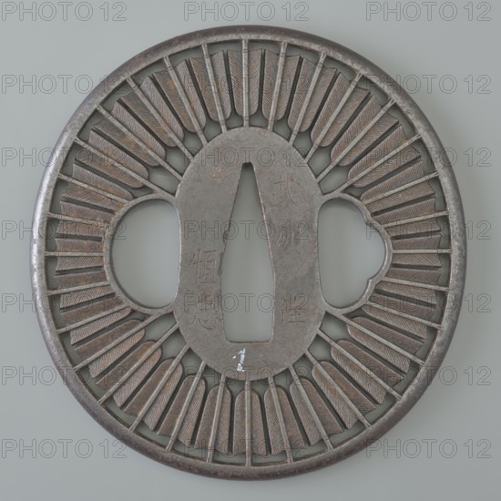 Crossguard tsuba, Tsunetada,  craftsman; decorated with an openwork positive design of thirty-two concentrically arranged arrow shafts and feathers with fine engraved details; Bushu Musashi referenced one of the fifteen ancient Japanese provinces along the Tokaido route; today's Tokyo-fu, Saitama-ken and Kanagawa-ken. 19th century Edo period, 1603–1868, Japan; Kawagoe. Tsuba round maru-gata with rounded edge, maru-mimi. Height 7.2 cm; width 7.0 cm; depth 0.3 cm., A round metal object with a central elongated diamond-shaped opening and two rounded side openings, featuring a decorative radial pattern of textured, tapered bars around the center; the metal surface shows a mix of dark gray and brownish tones with areas of lighter metallic highlights and some subtle rust-colored spots, and the background is a pale gray.