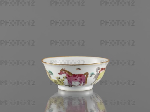 Bowl, colored porcelain, Qing style, decorated with landscape motifs and horses on the outer wall; bowl on a ring-shaped foot; 19th century, China; height 5 cm, diameter 11.8 cm., A small white porcelain bowl with a thin gold rim sits on a reflective surface against a neutral gray background, decorated around its exterior with painted animals including a pinkish-red horse and a yellow creature, with accents of green and brown in the foliage and other details, and the bowl’s reflection visible below showing softened colors and shapes.