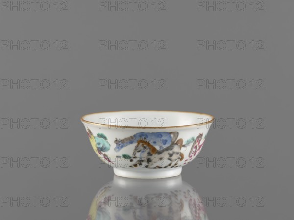 Bowl, ceramics, colored porcelain, Chinese, Qing dynasty 1644–1911, 19th century. Bowl on a ring-shaped foot, decorated on the outer wall with landscape motifs and horses. Vessel, height 5 cm, diameter 11.8 cm. Maker, inscription: Krieg doctor noted., A small porcelain bowl with a rounded rim and short foot sits on a reflective surface against a grey background; the bowl is primarily white with a thin gold band along the rim and painted decorations around its exterior showing a group of stylized animals and foliage rendered in colors including blue, yellow, green, brown, grey, and pink, with the reflection of the bowl and its painted motifs visible on the surface below.