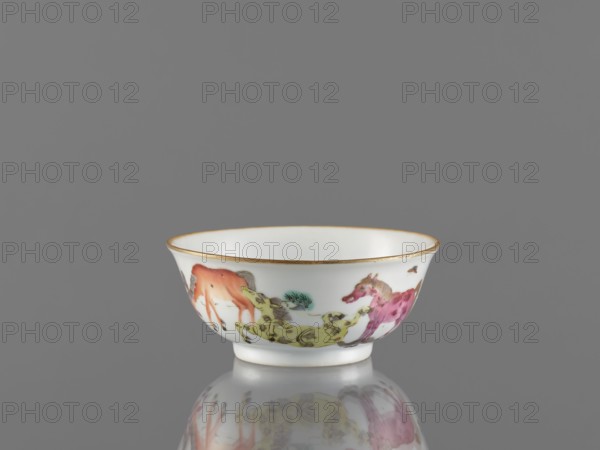 Bowl, ceramics, colored porcelain, Qing style 1644–1911, Chinese, 19th century. Porcelain bowl on a ring-shaped foot, height 5 cm, diameter 11.8 cm. Decorated on the outer wall with landscape motifs and horses. Maker, inscription or attribution: Krieg doctor noted. Repossession/provenance noted Jelenia Góra., A small white porcelain bowl with a thin gold rim sits on a reflective grey surface against a grey background; the bowl is decorated with painted horses in a range of colors including orange, yellow-green, pink, and muted green, with small accents of brown and black in the details, and the reflection of the bowl and its painted design is visible on the surface beneath it.
