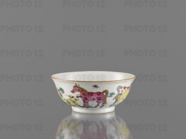 Bowl, colored porcelain, landscape motifs, Qing style, Chinese, horses, bowl on a ring-shaped foot, decorated on the outer wall, 19th century Qing, 1644–1911, China, vessel, height 4.8 cm, diameter 11.7 cm, A small shallow ceramic bowl with a rounded rim and a short foot sits centered against a plain gray background and casts a soft reflection below; the bowl is primarily white with a thin gold band along the rim and painted decorations around its exterior featuring a few stylized animals in pink, yellow, and brown with accents of green and blue, and there is a small multicolored insect-like motif above the animals.