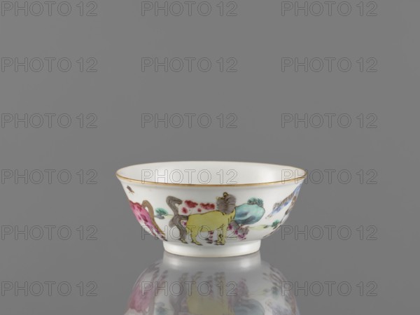 Bowl, ceramics, colored porcelain, landscape motifs, Qing dynasty 1644–1911, Chinese, horses, bowl on a ring-shaped foot, decorated on the outer wall, 19th century China, vessel, height 4.8 cm, diameter 11.7 cm, A small white porcelain bowl with a thin gold rim sits on a reflective surface; the bowl's exterior features a painted scene in pastel and brighter colors including yellow, pink, blue, green, brown, and grey, depicting stylized animals and decorative floral or cloud-like motifs, and the bowl casts a soft mirrored reflection below it against a plain grey background.