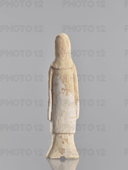 Figure of a standing woman — funerary figurine; creator, sculptor: Krieg doctor author; images of women; figurines; Chinese art; Chinese culture; repossession provenance; repossession Jelenia Góra; female figurines; 10th century ; China; sculpture; height 25.3 cm, A slender upright figurine made of a pale beige material stands against a neutral gray background, showing a smooth elongated head and a simple cylindrical body with minimal facial or anatomical detail; the surface has a weathered texture with patches of slightly darker beige and off-white, and there are worn areas and small irregular marks across the form; the figure’s arms appear as narrow vertical projections along the sides, and the lower portion flares into a bell-shaped base with uneven edges and small chips; overall colors visible are beige, off-white, and gray.