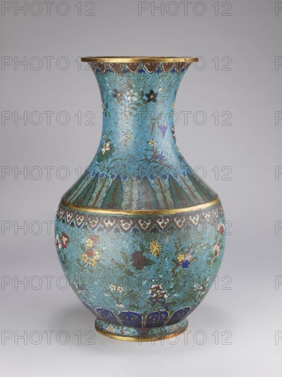 Vase, Qing style, Chinese culture, Chinese art, Qing 1644–1911; 18th/19th century, China. Porcelain vessel with a thick cylindrical neck and a flared spout, decorated with chrysanthemums, peonies, plum trees, meander ornament and plant motifs. Height 61.5 cm; diameter 25.7 cm; weight 10.0 kg., A rounded decorative vase with a flared neck, shown against a neutral gray background, featuring an overall turquoise-blue ground covered with an interlocking geometric pattern and scattered floral motifs; the body displays painted flowers in colors including white, yellow, red, purple, and dark blue, with green foliage; a band of stylized leaf or feather forms in green and dark blue separates the neck from the shoulder, and a repeating heartlike border in dark blue and white runs near the widest point; the rim and foot are highlighted with metallic gold-colored bands, and the lower foot area includes a row of dark blue petal shapes with lighter blue accents; the surface shows areas of darker pat...