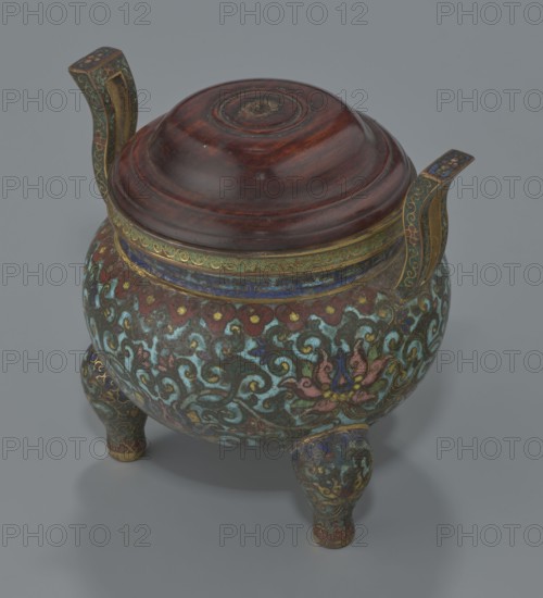 Ding-type incense burner with cover, Chinese, Qing dynasty, Qianlong period 1736–1795; ceremonial ding vessel/censer decorated with lotus plant ornament; incense burner, vessel; height 11.5 cm, diameter 11.0 cm; 1736–1795; China., The image shows a decorative tripod vessel with a domed wooden lid in a dark reddish-brown color resting on a rounded body supported by three short, curved legs; the body and legs display an ornate cloisonné-like pattern in turquoise, teal, blue, green, red, pink, gold, and brown with swirling floral and foliate motifs, and the rim and two upward-facing handles are accented with gold and blue decorative bands.