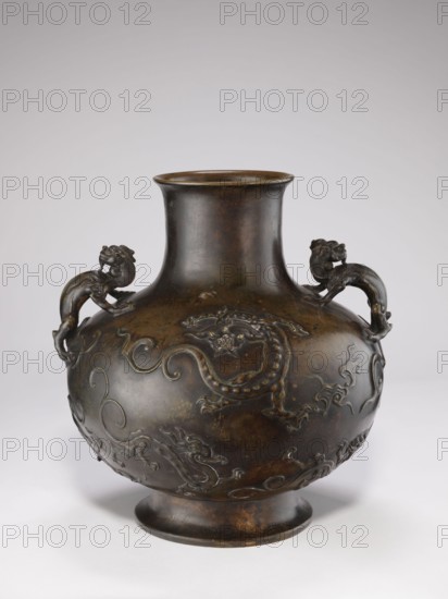 Vase with two dragon-shaped handles qiulong, maker, gift; Chinese art, Chinese culture; Qing dynasty 1644–1911, Qing style; dragons iconography; backdated signatures; belly in the shape of a flattened sphere; low, round foot; cylindrical short neck with a very slightly flared spout; 19th century, China; vessel; height 38 cm; diameter 15 cm; weight 10.0 kg, A dark brown rounded metal vessel with a narrow neck and flared rim sits against a light gray background, featuring a pair of sculpted animal handles on opposite sides near the shoulder and raised decorative motifs of mythical creatures and flowing cloudlike scrolls around its bulbous body, with a slightly flared foot supporting it; visible colors include dark brown, lighter brown highlights, and hints of black and gray.