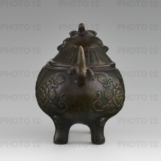 Incense burner with cover - qilin, Paderewski, Ignacy Jan 1860-1941, Chinese art, Chinese culture, Qing 1644-1911, Qing style, peonies, qilin iconography, unicorns iconography. Incense burner on four legs. Decoration in flat relief. 18th century, China. Incense burner. Height 10.5 cm, diameter 10.0 cm., A rounded three-legged bronze vessel with a lid, shown against a neutral gray background, displaying a dark brown and greenish patina. The body of the vessel is bulbous with a slightly narrower shoulder and rests on three short, curved legs. A handle or spout-like projection extends from the shoulder toward the viewer. The surface of the body has raised decorative motifs in a slightly lighter bronze tone, including floral and curling designs. The lid is domed with ribbed sections and a small sculpted finial on top, all sharing the dark brown and greenish bronze coloration. The overall tones visible are dark brown, bronze, and green.