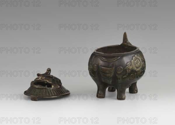 Incense burner with cover - qilin; maker, gift; Chinese art; Chinese; Qing dynasty 1644–1911; 18th century, China; incense burner on four legs with cover; decoration in flat relief featuring peonies and qilin unicorns iconography; height 10.5 cm, diameter 10.0 cm., A small metal vessel and a separate lid rest on a neutral surface against a gray background; the vessel is rounded with three short legs and a pointed projection at its rim, showing raised floral and circular decorative motifs, and the lid has a sculpted form with an open mouth-like opening and a flared, ridged base. The visible colors include dark brown, greenish patina, and hints of gold on the raised decoration, with the background and surface in shades of gray and white.