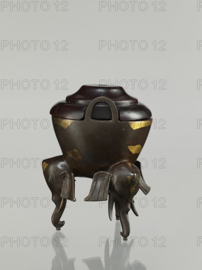 Censer with cover, Chinese art, Chinese culture, Qing 1644–1911, elephants, ceremonial vessel. Censer with two arched handles; convex cover with two offsets. 19th century, China. Censer; height 21.1 cm, diameter 14.3 cm., A small sculptural object with a rounded dark brown lid sitting on a bulbous dark bronze body that shows areas of worn gold-colored patches, supported by a group of stylized elephant-shaped legs in dark bronze with subtle gold highlights; the lid has a smooth, slightly glossy finish and a raised central form, the body has a matte metallic surface, and the elephants feature curved trunks and flared ears.