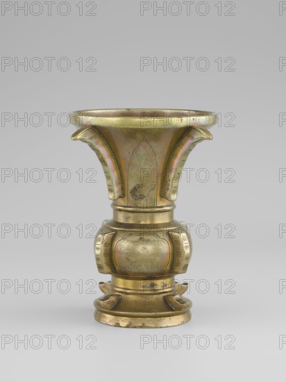 Gu-type vase, Vase with a shape inspired by the cult vessel gu, with four convex, interrupted strips. Decoration: on the belly in oval reserves stylized peonies on a grained background. Ceremonial/ritual vessel, Qing dynasty 1644–1911, 19th century China. Porcelain/ceramic vessel, height 16 cm, diameter 12.2 cm., A metallic vessel with a flared rim and a rounded base, displaying a warm golden color with areas of greenish and purplish iridescence and darker tarnished spots; the upper section flares outward with three curved, ribbed projections extending downward, each showing subtle linear incisions; the midsection narrows into a cylindrical neck that leads to a bulbous, paneled body decorated with shallow carved motifs and recessed rectangular panels on its sides, all in the same golden tone with slightly darker engraved lines; the lower section steps down into a circular foot with layered rings and small curved adornments around its perimeter, showing patches of wear and darker discol...