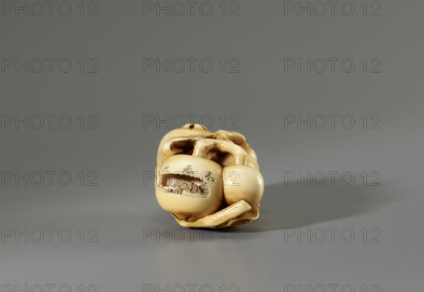 Netsuke in the shape of a twig with biwa loquat fruits, Gyokuhôsai Yamada Bunjiro, active in Edo, 2nd half 19th century, ca. 1850–1860 Kaei 5–Ansei 7. Ivory carving engraving, netsuke katabori, height 2.0 cm, width 4.2 cm, depth 2.8 cm. Signed Gyokuhosai. Miniaturized, naturalistic depiction of a biwa branch; the artist carved three microscopic landscapes above the fruits identified by inscriptions as Shinobazu Pond, the Tama River, and the Sengenyama plateau. Sculpture, Japan, 2nd half of the 19th century., A small carved object rests on a flat surface against a plain background, showing a smooth, polished surface in shades of cream, beige, and light brown with darker brown accents in crevices; the carving features rounded, organic forms with a hollowed opening revealing detailed interior texture and a few incised marks on the exterior, and soft shadowing extends to the right on a gray surface under soft, diffuse lighting.